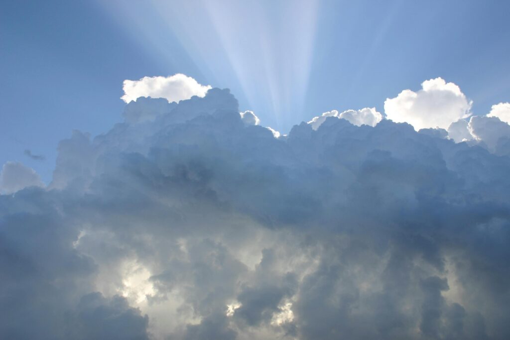 Stunning cumulus clouds and sunrays against a clear blue sky, perfect for nature themes.