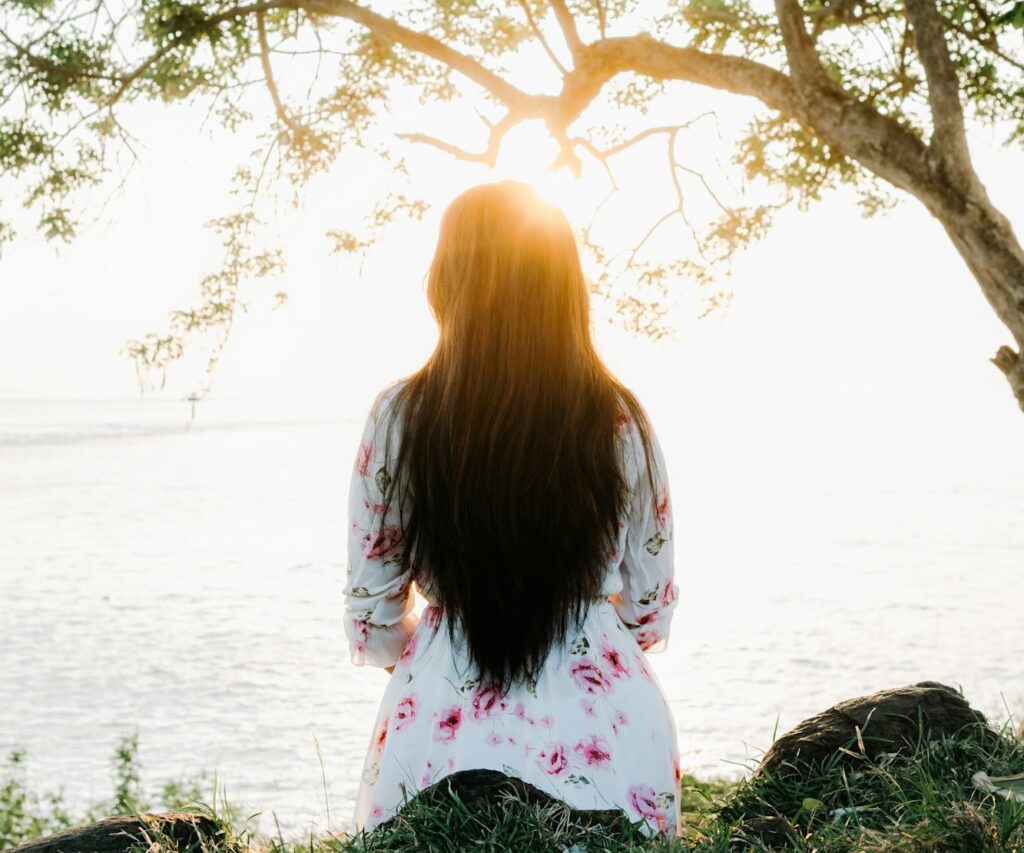 Woman sitting under a tree at sunset