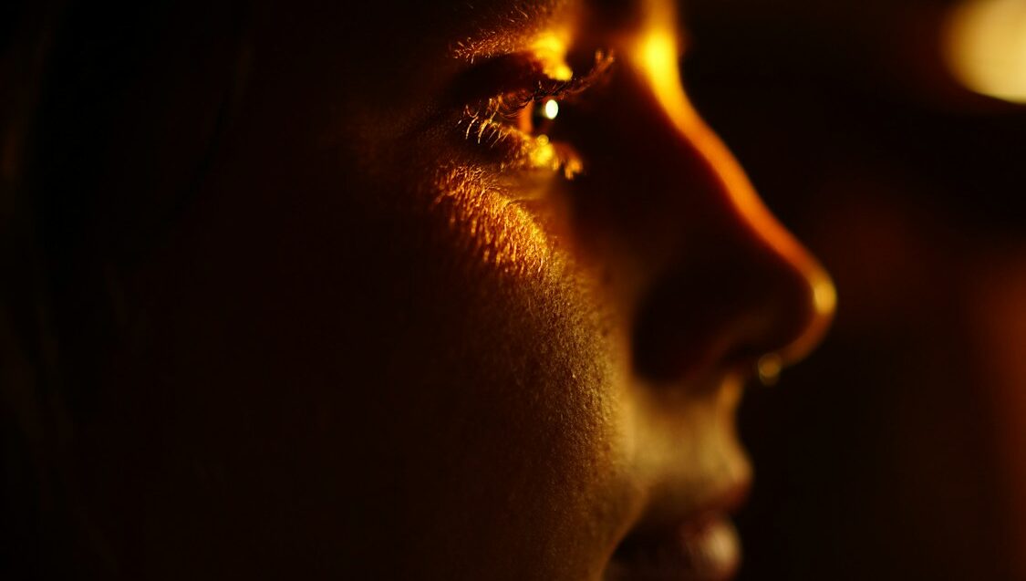 a woman in the dark with her hand on her face