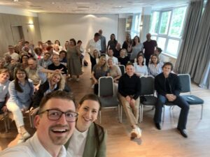 Dr Rafał Szewczyk i dr Marta Szewczyk na tle sali pełnej menedżerów PKO BP po wykładzie o inteligencji emocjonalnej