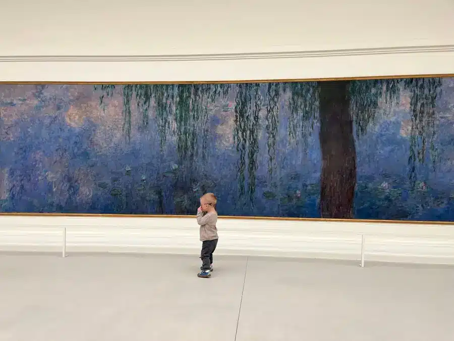 Mały chłopiec przed obrazem z liliami wodnymi w muzeum