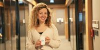 a woman holding a cup of coffee in a hallway